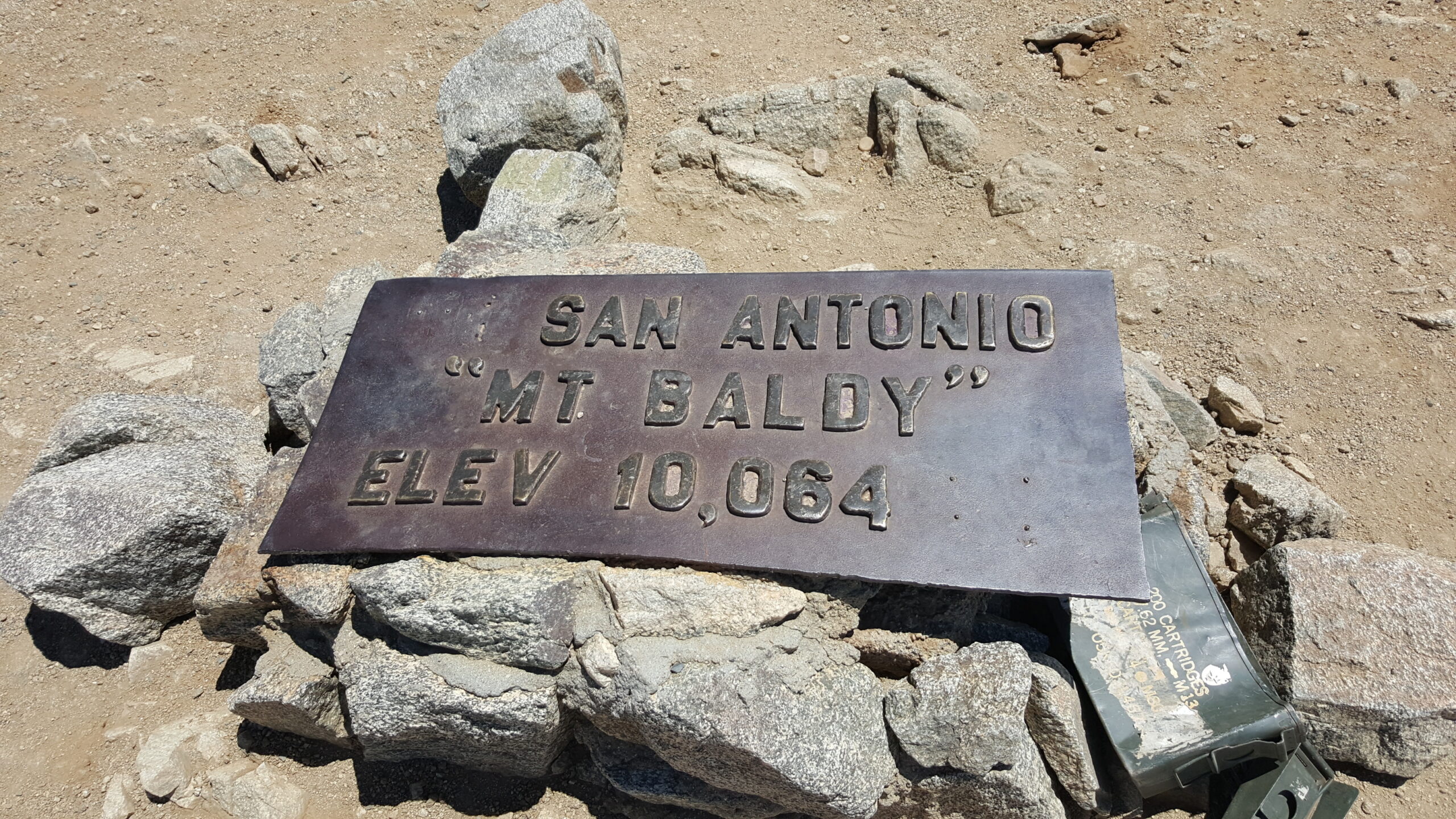 The summit plaque rests on a pile of boulders
