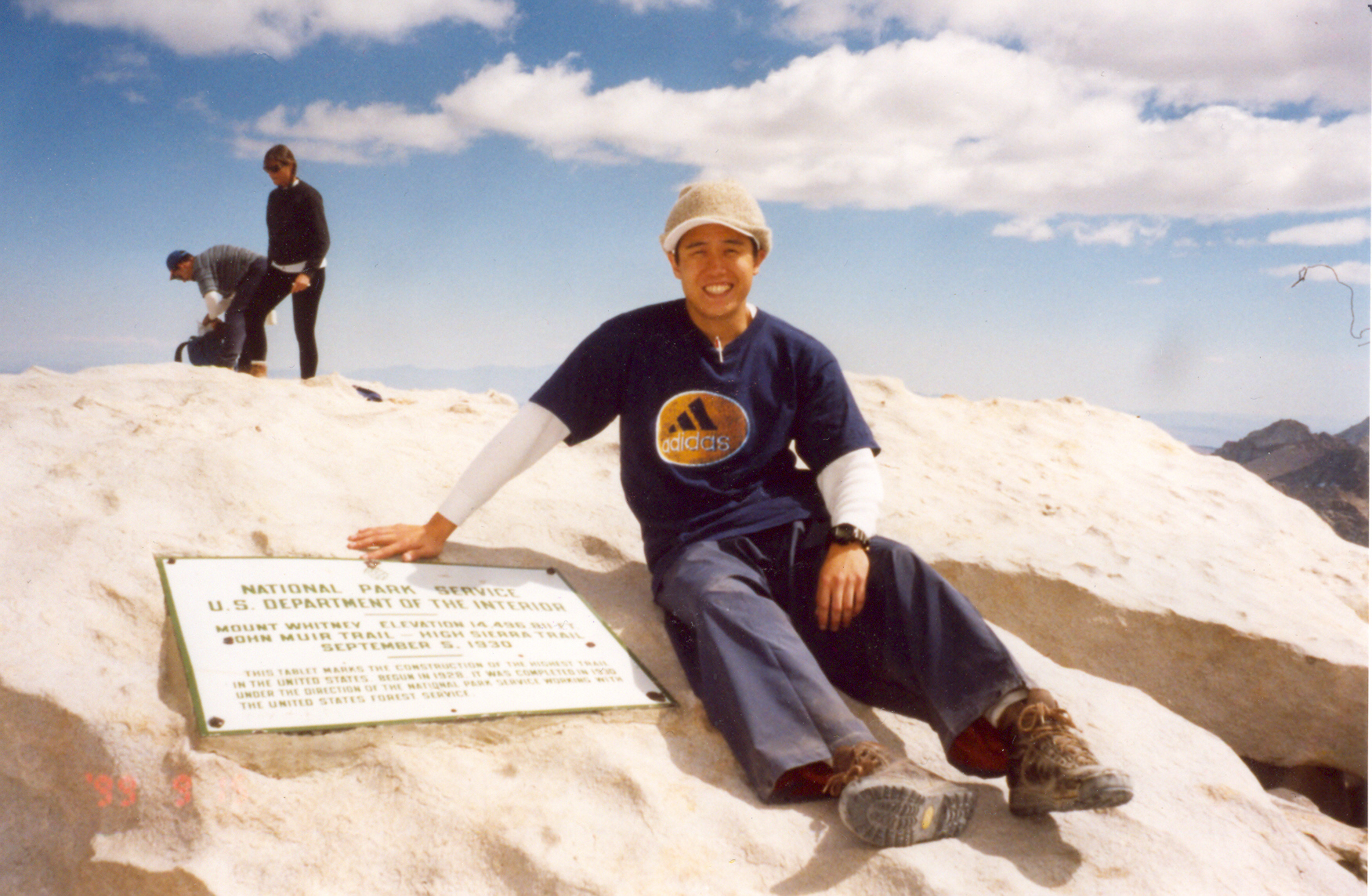 A photo of the author sitting on the summit of Whitney
