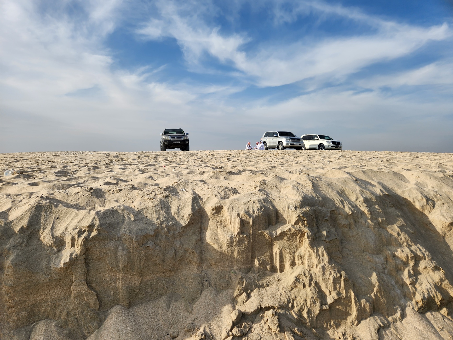 Three 4x4 SUVs parked high on a sandy bluff