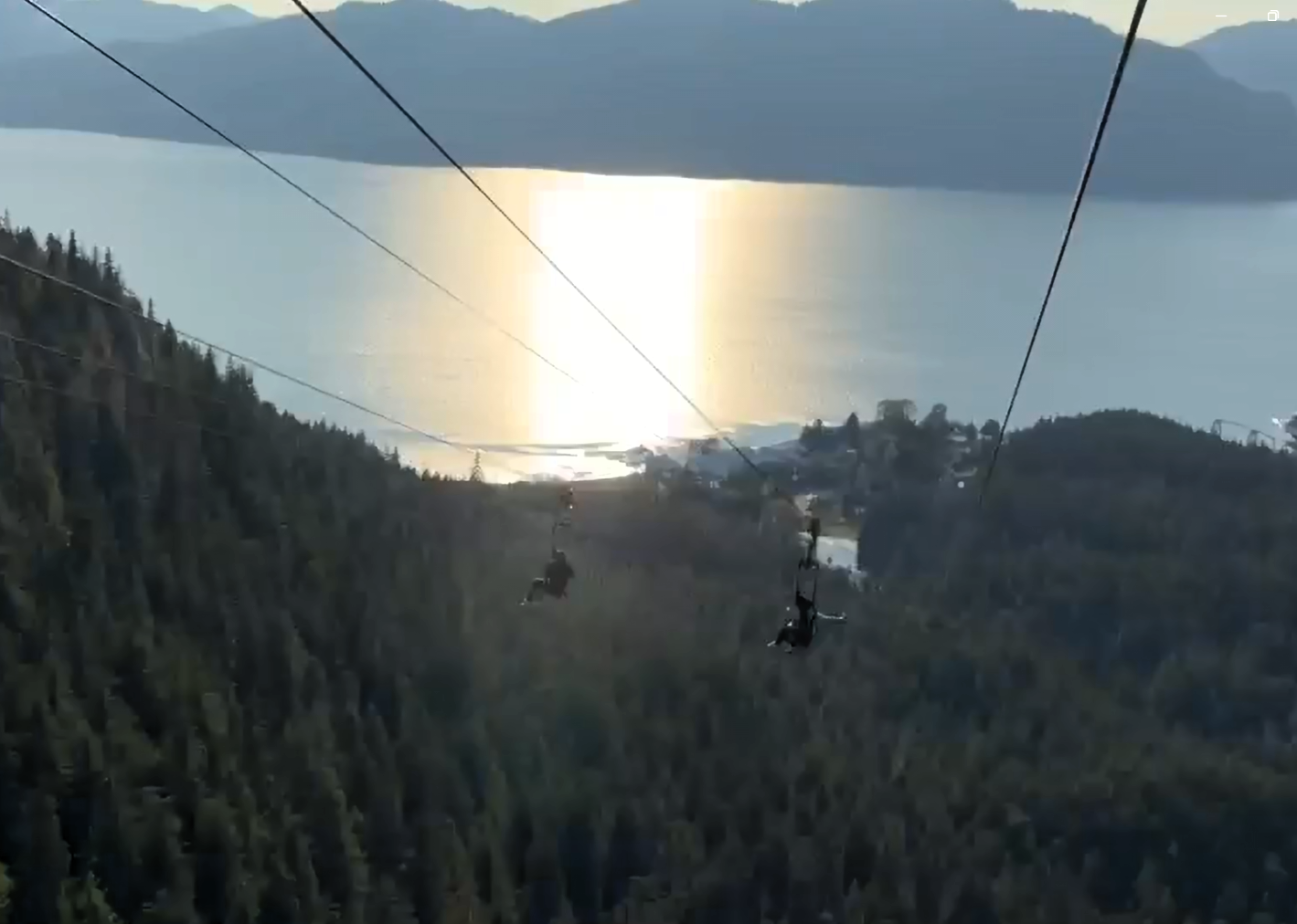 Two riders appear to soar through the air like an eagle above the green treetops and shining sea.